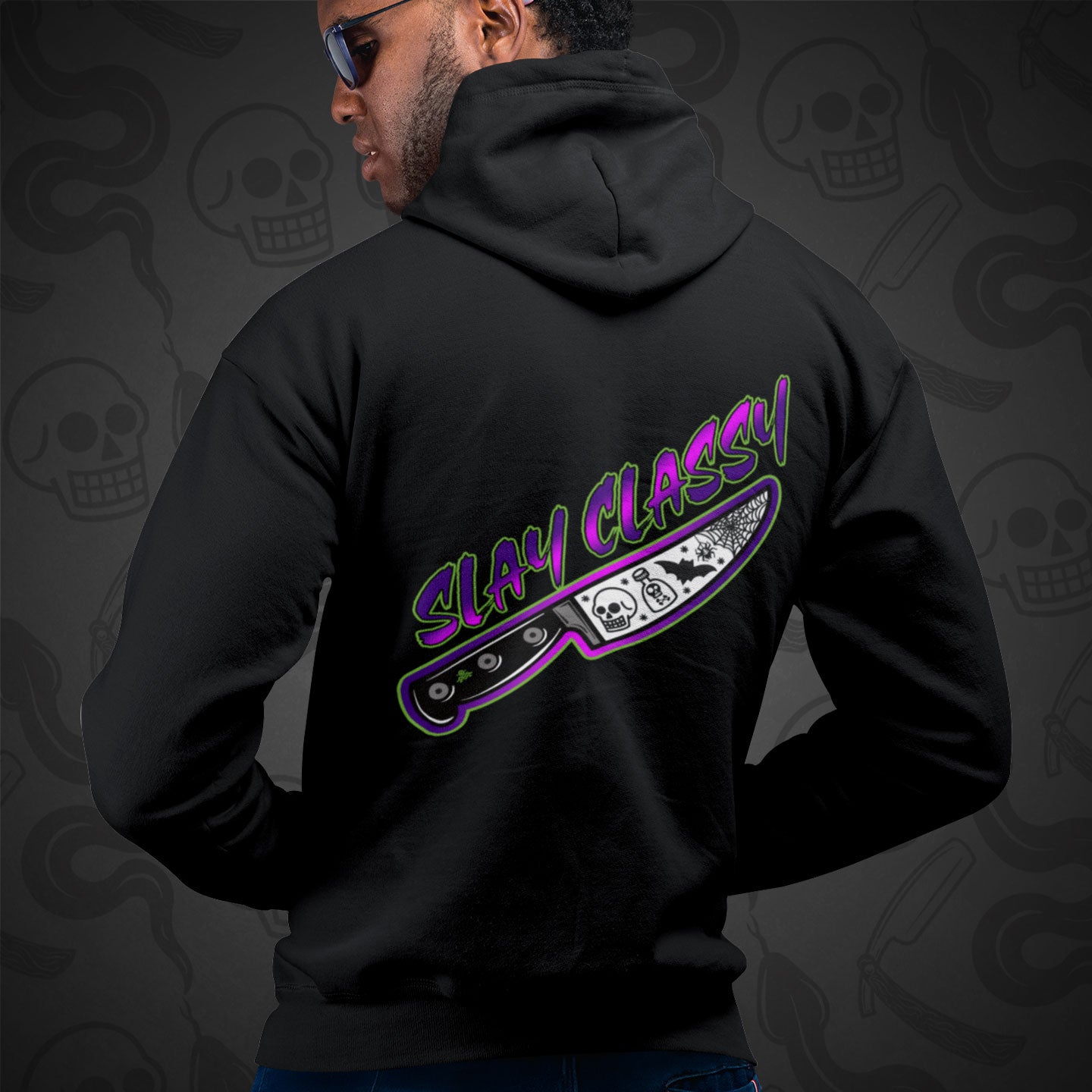 Cropped image of a Model wearing a black zippered hoodie with Slay Classy design printed on the back with vibrant colors.